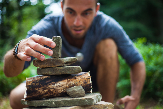 homme qui construit une pyramide en petits caillioux