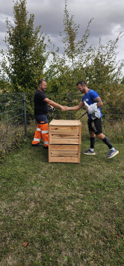 2 hommes se donnent une poignée de main derrière le composteur.
